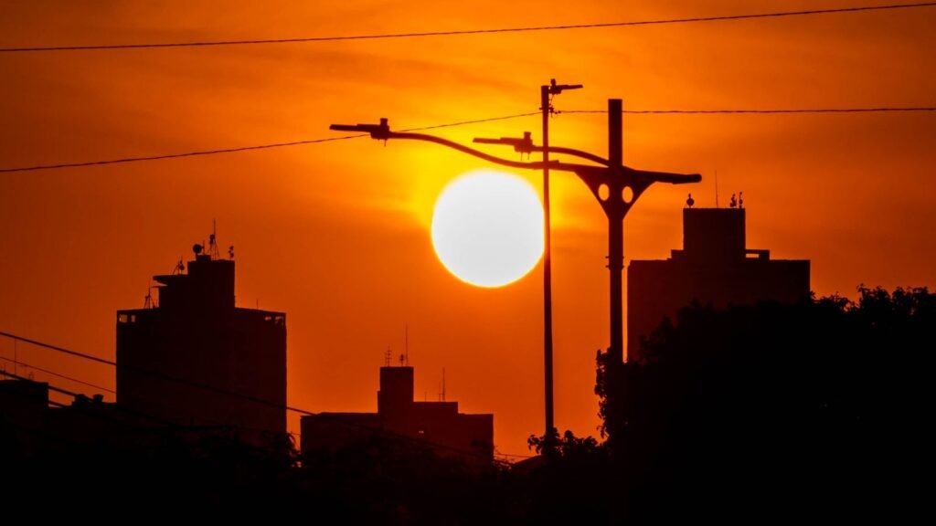 Canicule : soleil brûlant sur un ciel rouge au-dessus des toits